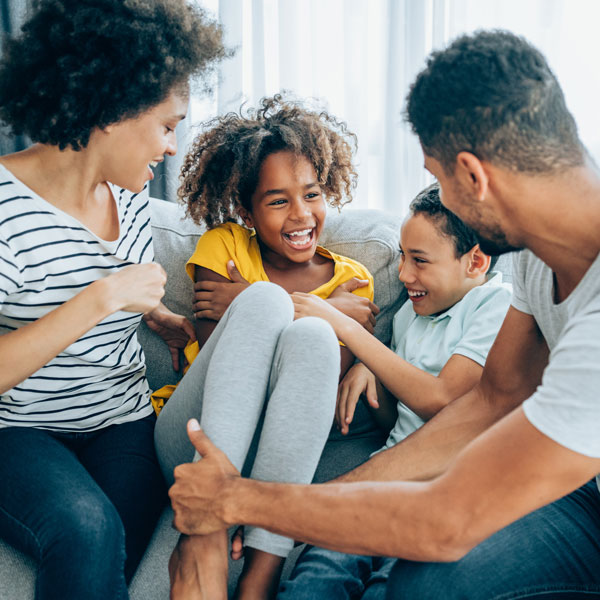 family of four laughing on couch
